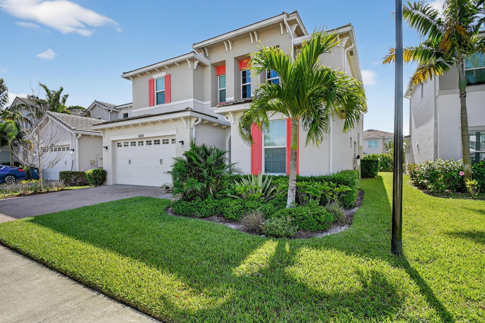 A two-story suburban house with a white garage, beige stucco siding, and bright red shutters — 5632 Liberty Lane, Westlake FL 33470, WESTLAKE, FL