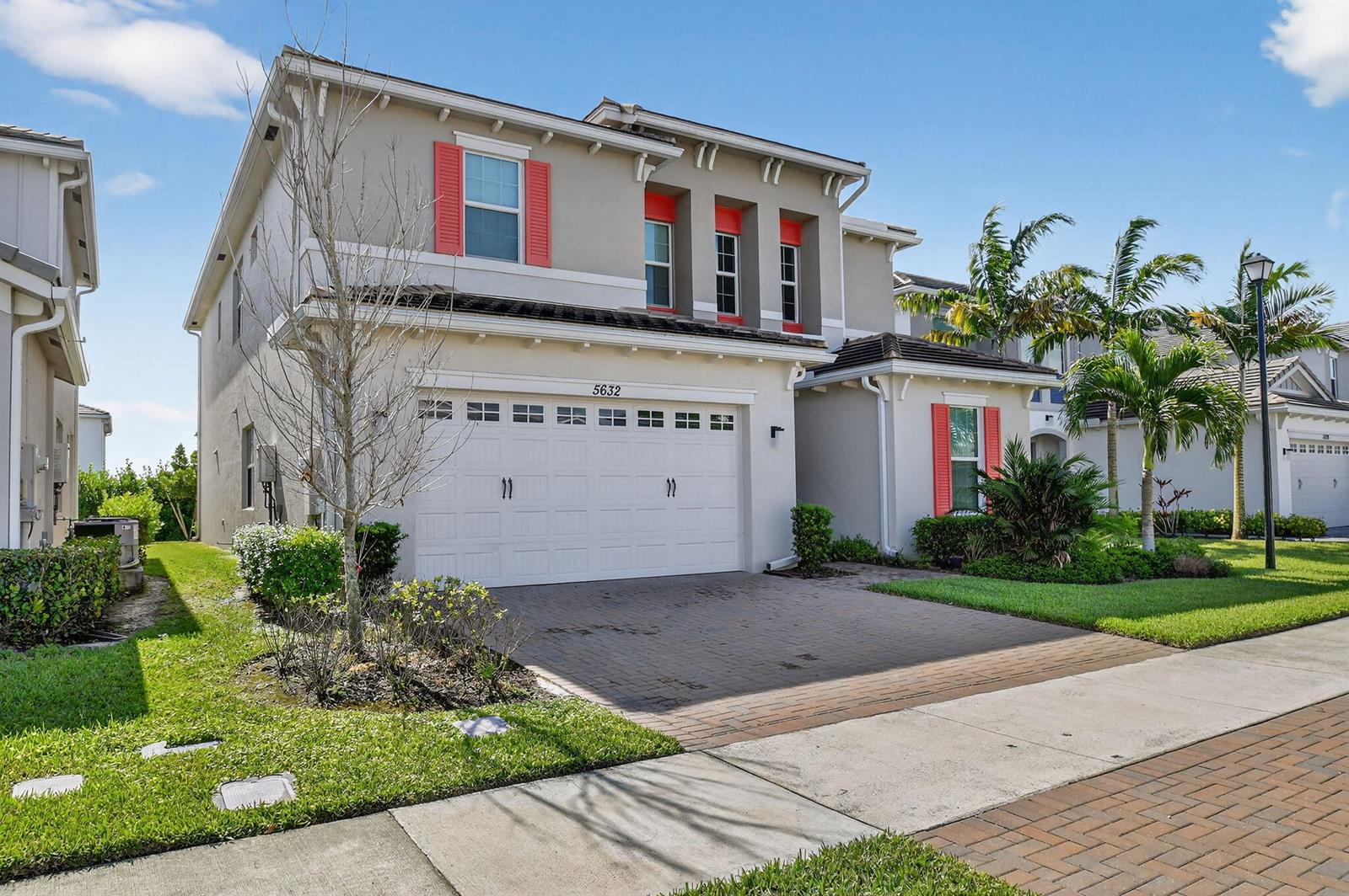 A two-story suburban house with a white garage, beige stucco walls, and red shutters — 5632 Liberty Lane, Westlake FL 33470, WESTLAKE, FL