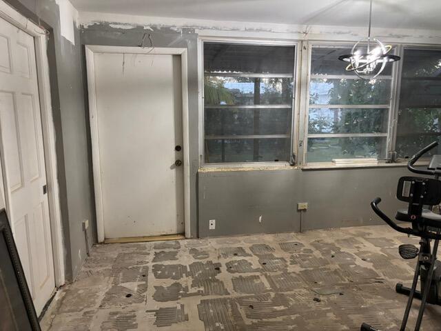 An unfinished room with gray walls, a white door, large windows, and exposed concrete flooring — 360 Leisure Boulevard, Pompano Beach FL 33064, POMPANO BEACH, FL