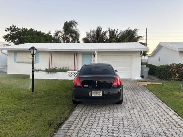 A white single-story house with a black sedan parked in the paved driveway — 360 Leisure Boulevard, Pompano Beach FL 33064, POMPANO BEACH, FL