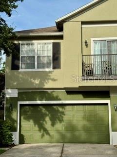 A two-story house exterior features a green garage door and a second-floor balcony — 1470 BROKEN OAK DRIVE UNIT 27C, WINTER GARDEN, FL