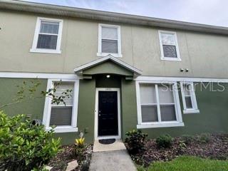 A two-story townhouse exterior with a dark front door, green stucco walls, and white trim — 1470 BROKEN OAK DRIVE UNIT 27C, WINTER GARDEN, FL