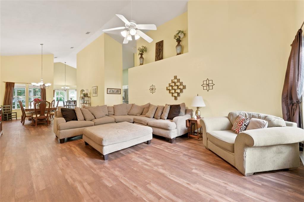 A spacious living room with high ceilings, light yellow walls, wood flooring, and neutral furniture — 3052 SW 94TH STREET, GAINESVILLE, FL