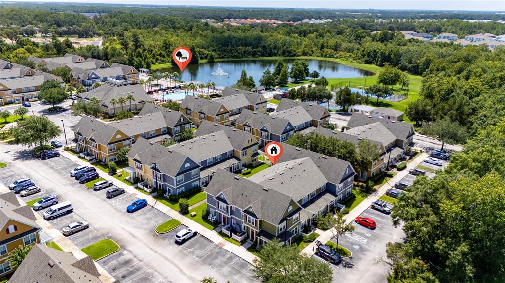 An aerial view shows multi-story apartment buildings with parking lots near a lake and pool — 2616 LODI CIRCLE UNIT 104, KISSIMMEE, FL