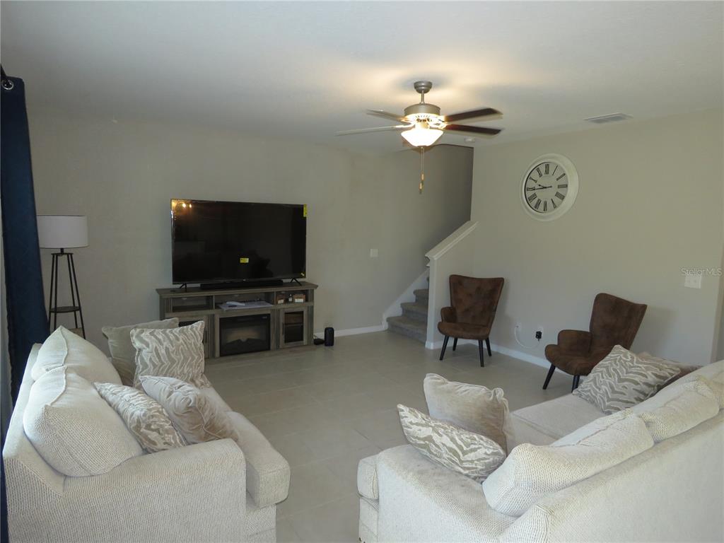 A living room features light tile floors, two sofas, two brown chairs, and a television — 15518 MILLER CREEK DRIVE, SUN CITY CENTER, FL