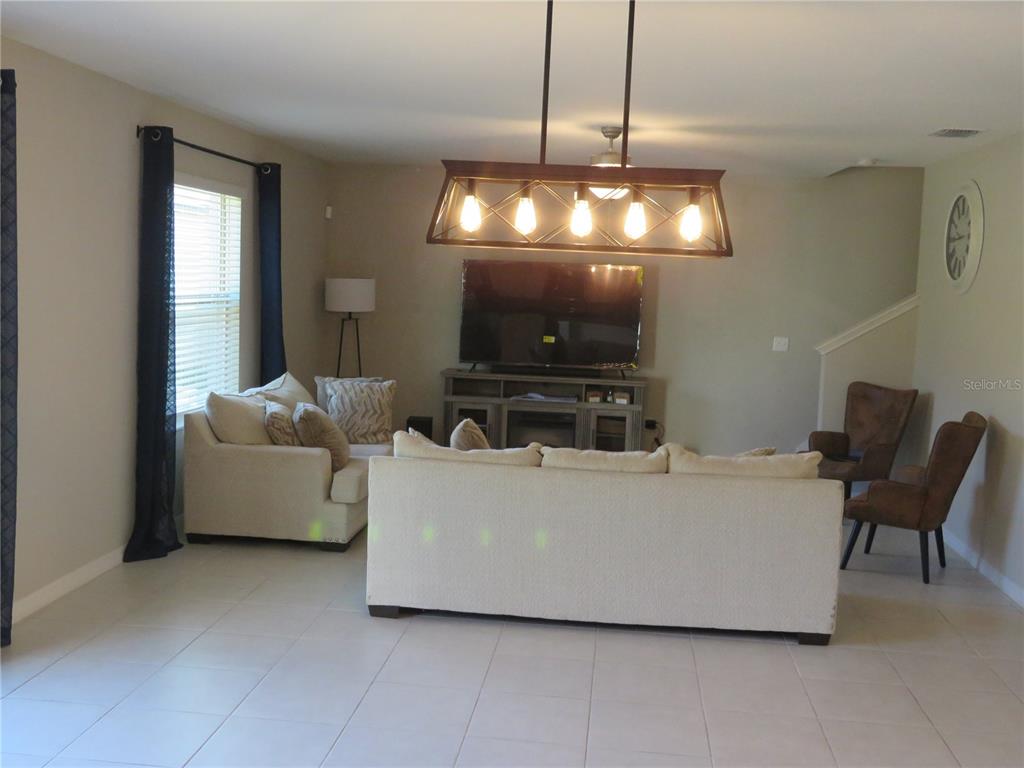 A living room features a large sofa, two armchairs, a television console, and a chandelier — 15518 MILLER CREEK DRIVE, SUN CITY CENTER, FL