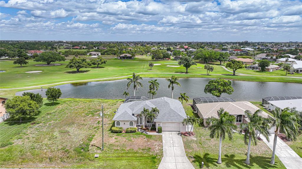 An aerial view shows a suburban house with a pool cage overlooking a golf course — 1511 NW 29TH PLACE, CAPE CORAL, FL
