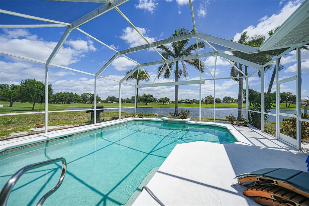 A screened-in swimming pool overlooks a lake and a golf course under a blue sky — 1511 NW 29TH PLACE, CAPE CORAL, FL