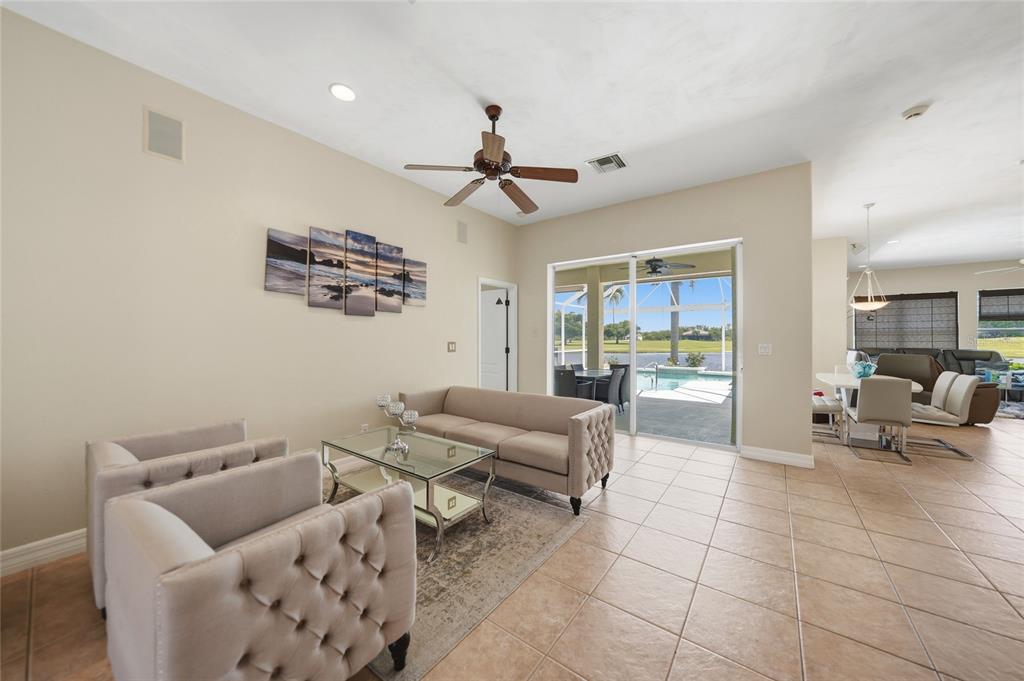 A living room with beige furniture, tile floors, and a sliding door leading to a pool — 1511 NW 29TH PLACE, CAPE CORAL, FL