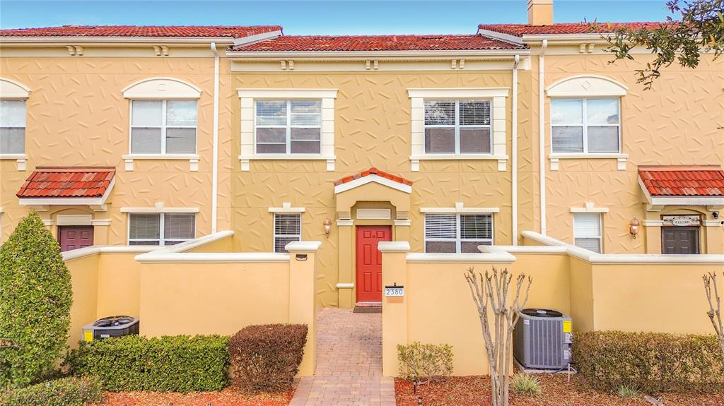A row of tan townhouses with red tile roofs and a central red front door — 2380 BELLA VISTA DRIVE, DAVENPORT, FL