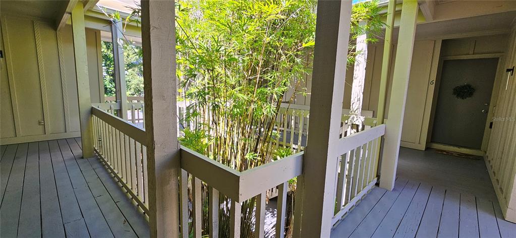An outdoor wooden walkway leads to a front door, featuring a central bamboo-filled atrium — 2232 BAHIA VISTA STREET UNIT A6, SARASOTA, FL