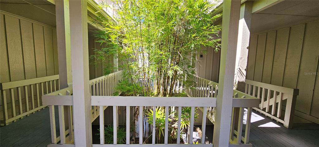 An outdoor walkway with wooden railings surrounds a central courtyard filled with bamboo plants — 2232 BAHIA VISTA STREET UNIT A6, SARASOTA, FL
