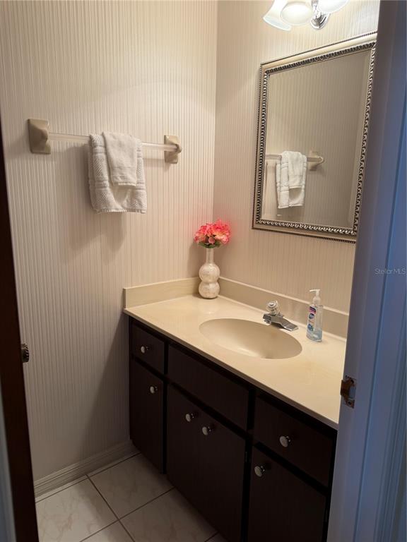 A small bathroom features a dark wood vanity, beige countertop, and a wall-mounted mirror — 924 RIDGECREST ROAD, ORLANDO, FL