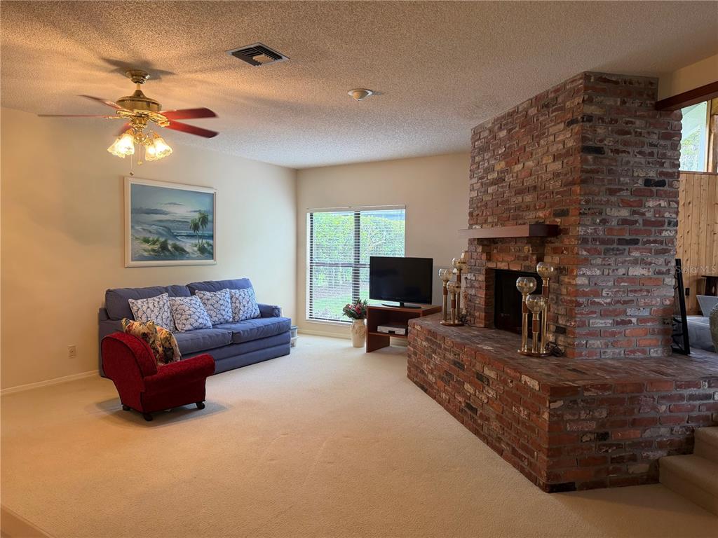 A living room features a large brick fireplace, beige carpeting, and a blue sofa — 924 RIDGECREST ROAD, ORLANDO, FL