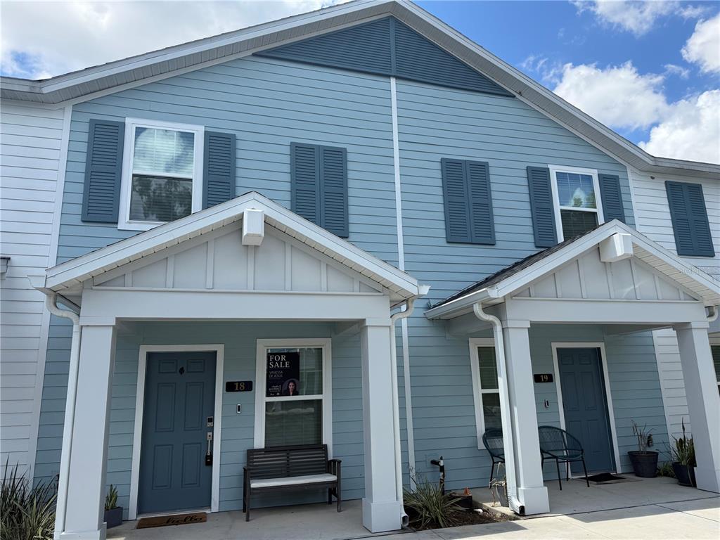 The exterior of two adjacent light blue townhomes with dark blue shutters and covered porches — 3409 SW 34TH AVENUE CIRCLE UNIT 18, OCALA, FL