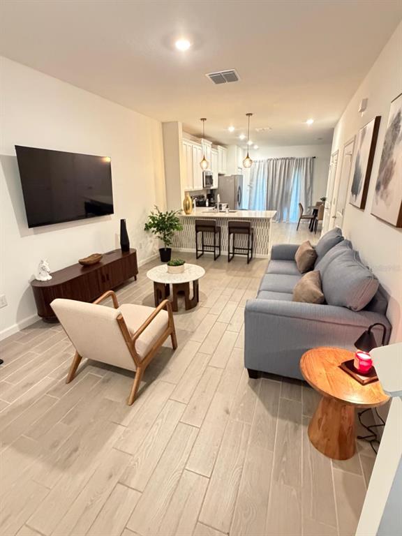 A living room with light wood-look tile floors, a blue sofa, and an open kitchen — 3409 SW 34TH AVENUE CIRCLE UNIT 18, OCALA, FL