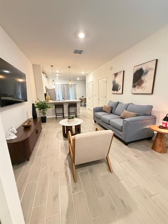 A living room with light wood-look tile flooring, a blue sofa, and an open kitchen — 3409 SW 34TH AVENUE CIRCLE UNIT 18, OCALA, FL