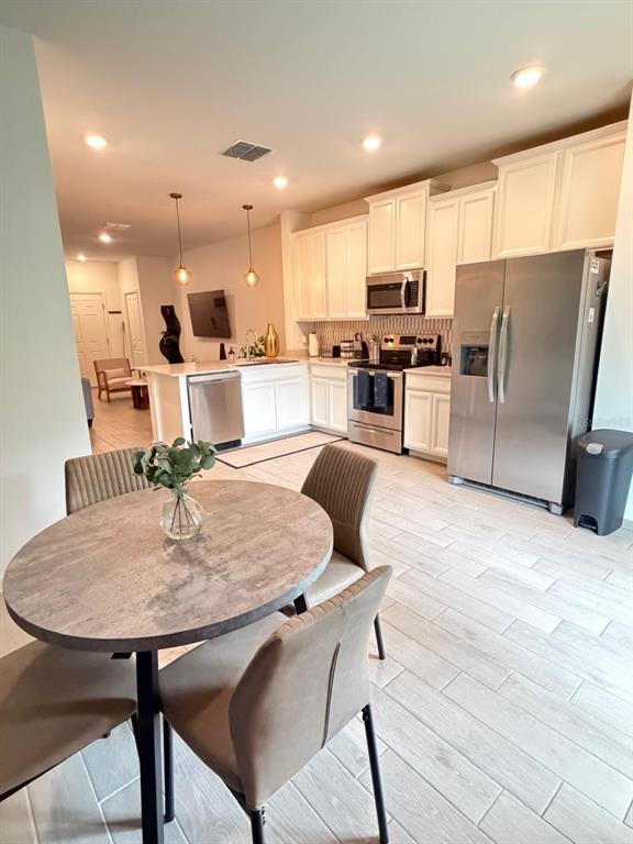 A kitchen with white cabinets, stainless steel appliances, and a round dining table — 3409 SW 34TH AVENUE CIRCLE UNIT 18, OCALA, FL