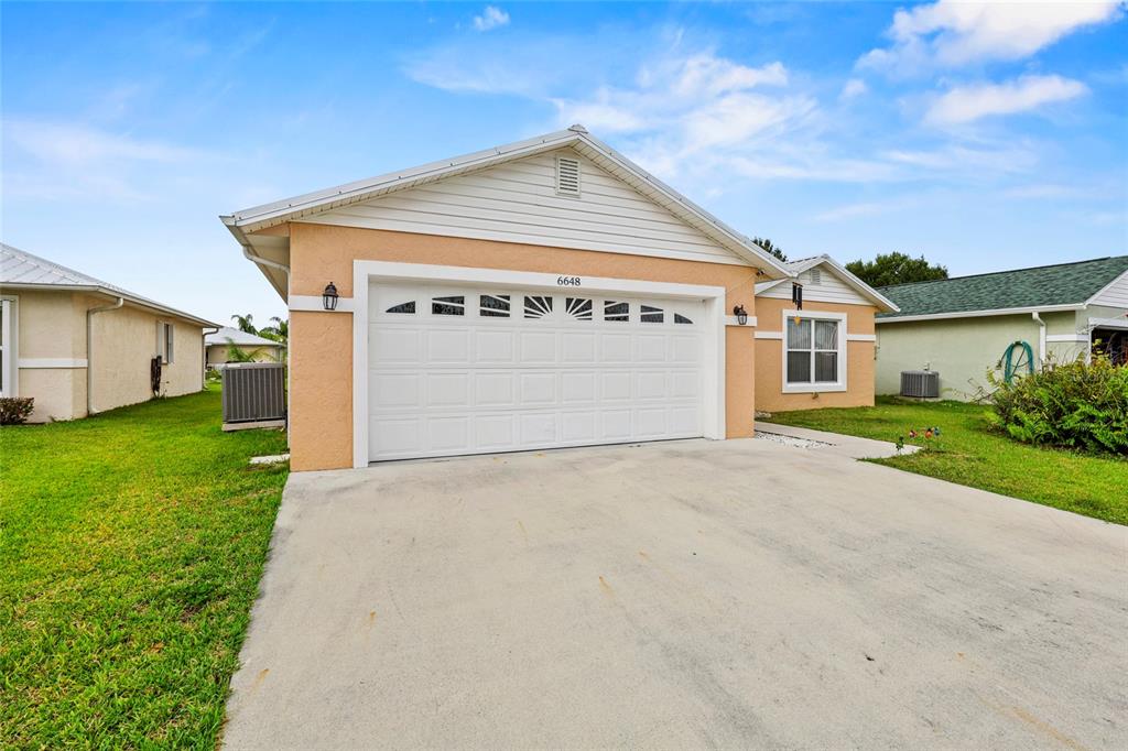 A single-story house with a peach-colored exterior, a white garage door, and a concrete driveway — 6648 GAVIOTA, FORT PIERCE, FL