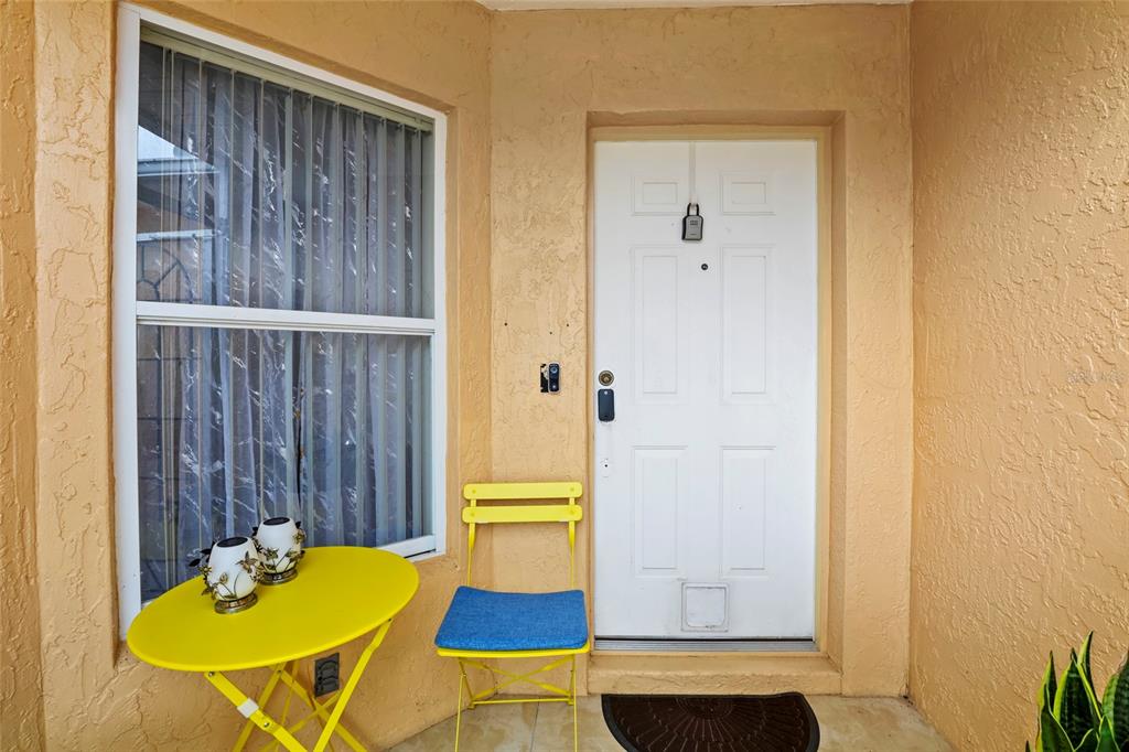 A yellow bistro set sits on a porch next to a white front door — 6648 GAVIOTA, FORT PIERCE, FL