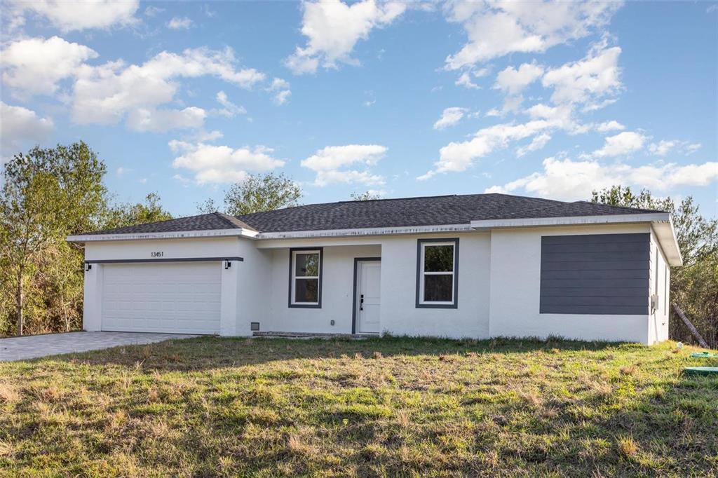 A single-story white house with a two-car garage and a dark gray accent wall — 13451 KAPLAN TERRACE, PORT CHARLOTTE, FL