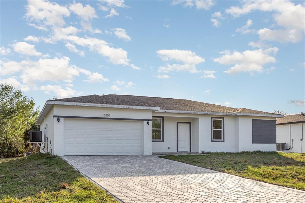 A single-story house with a white exterior, a paved driveway, and a two-car garage — 13451 KAPLAN TERRACE, PORT CHARLOTTE, FL