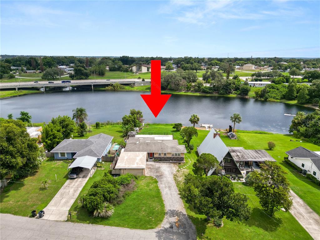 An aerial view shows a house with a pool cage situated on a lakefront lot — 228 W LAKE INA DRIVE, WINTER HAVEN, FL