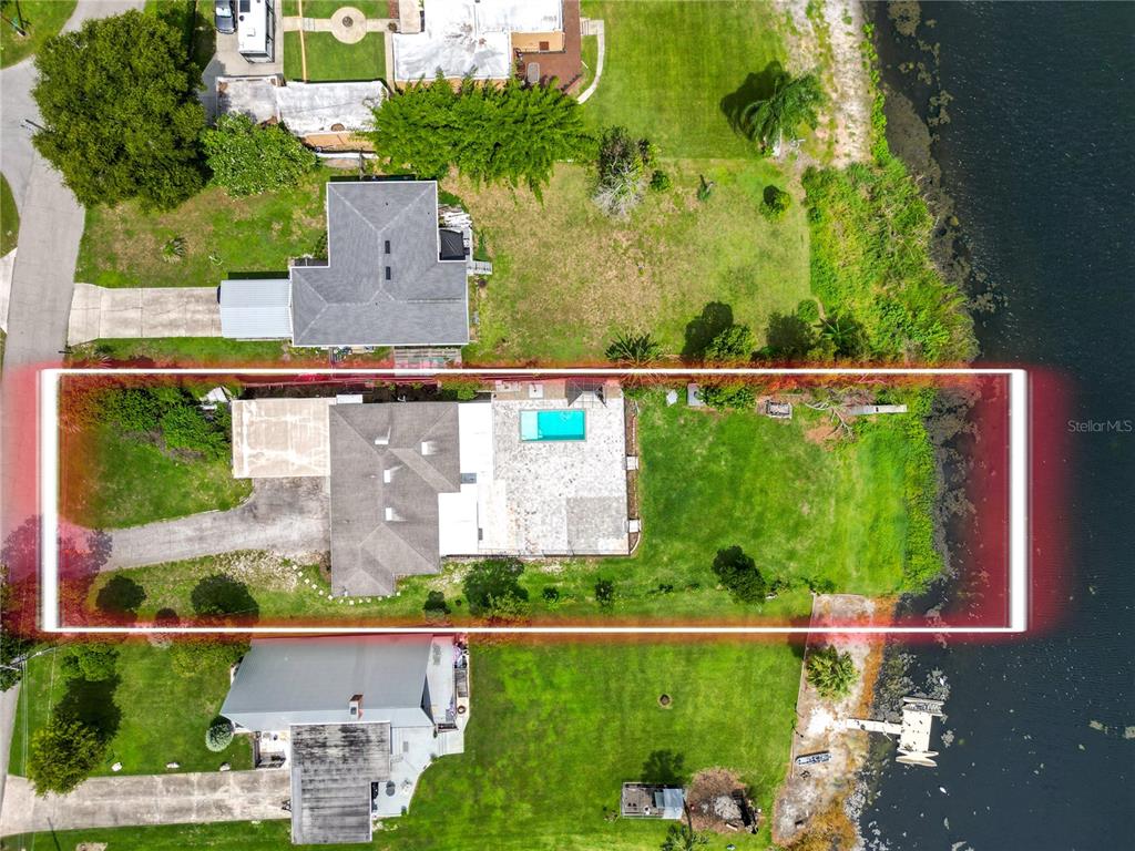 An aerial view shows a house with a swimming pool on a waterfront lot — 228 W LAKE INA DRIVE, WINTER HAVEN, FL