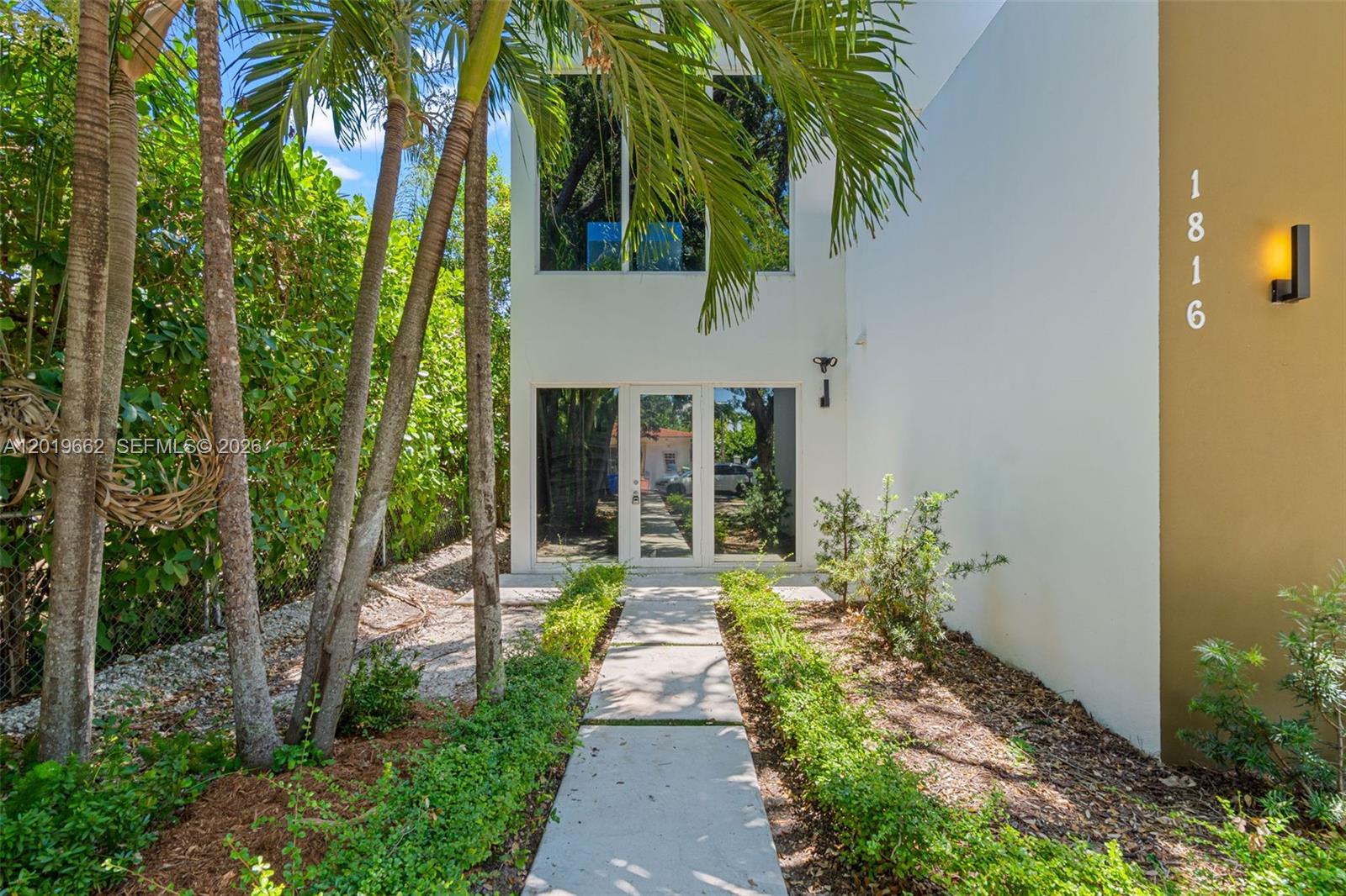 A modern white building entrance features a glass door, large windows, and a concrete walkway — 1816 SW 23rd St, Miami FL 33145, MIAMI, FL