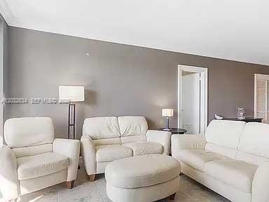 A living room features white leather furniture, a matching ottoman, and gray walls — 3000 S Ocean Dr # 420, Hollywood FL 33019, HOLLYWOOD, FL