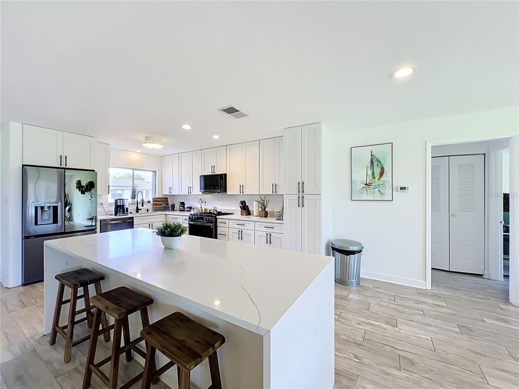 A modern kitchen features white cabinetry, a large quartz island, and stainless steel appliances — 5501 MEMORIAL DRIVE, ORLANDO, FL