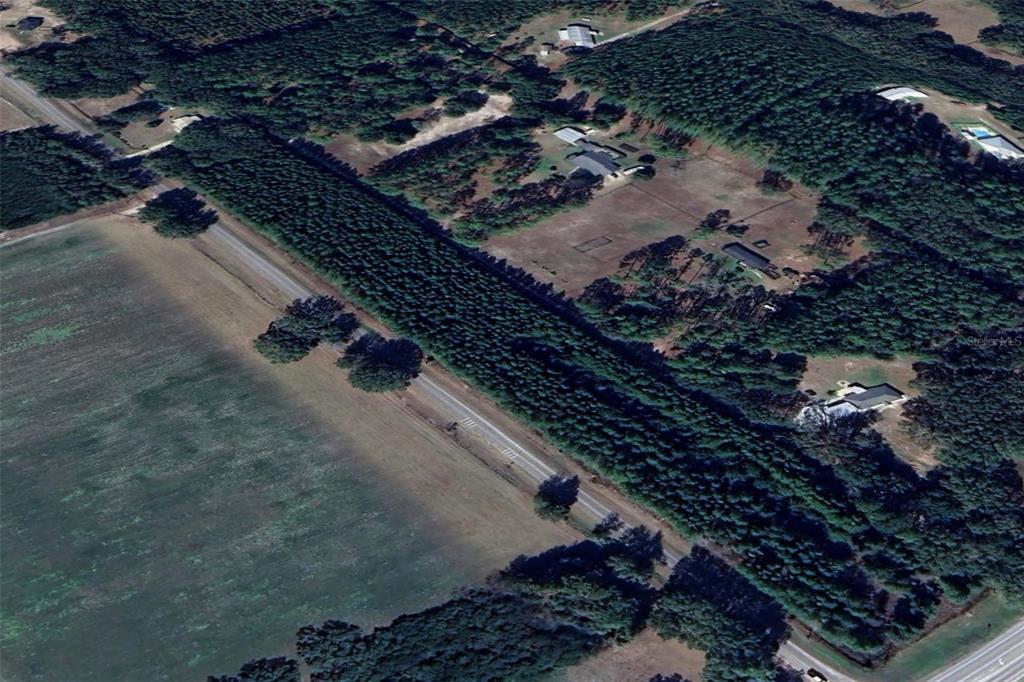 An aerial view shows a rural property with a road, open fields, and wooded areas — 7818 NW STATE ROAD 45, HIGH SPRINGS, FL