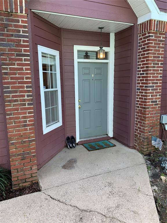 A front entrance with a gray door, a window, and a concrete porch — 350 NW 50 BOULEVARD UNIT 350, GAINESVILLE, FL