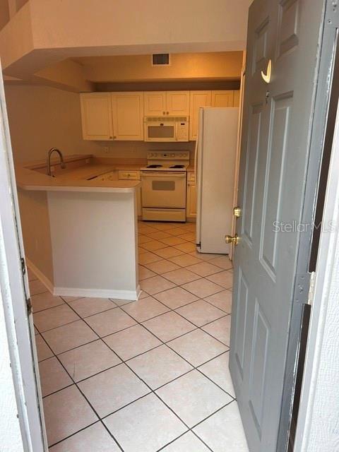 A kitchen with white cabinets, a white stove, and light-colored tile flooring — 350 NW 50 BOULEVARD UNIT 350, GAINESVILLE, FL
