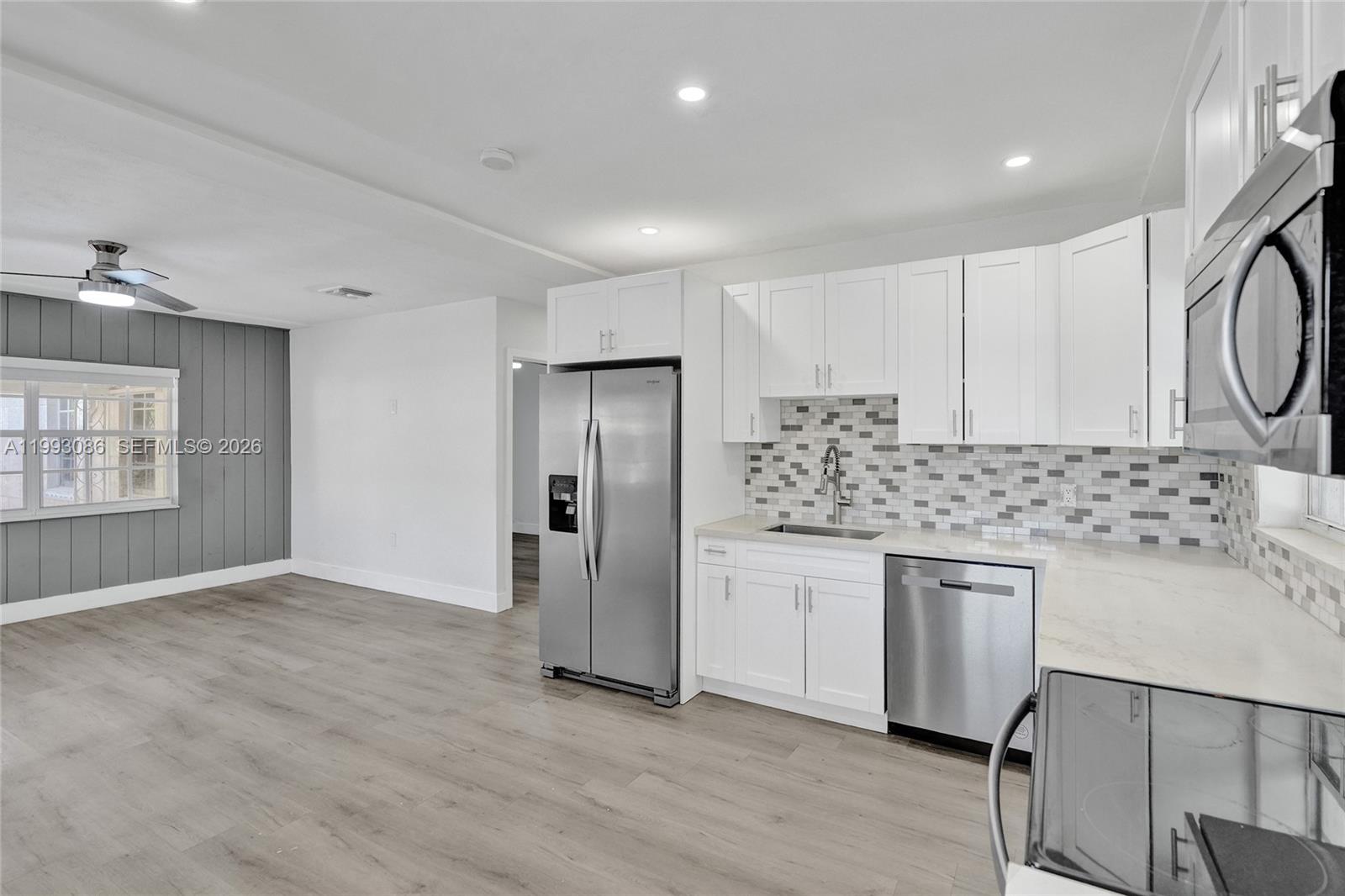 A modern kitchen features white cabinets, stainless steel appliances, and a gray tiled backsplash — 4326 NW 4th St, Miami FL 33126, MIAMI, FL