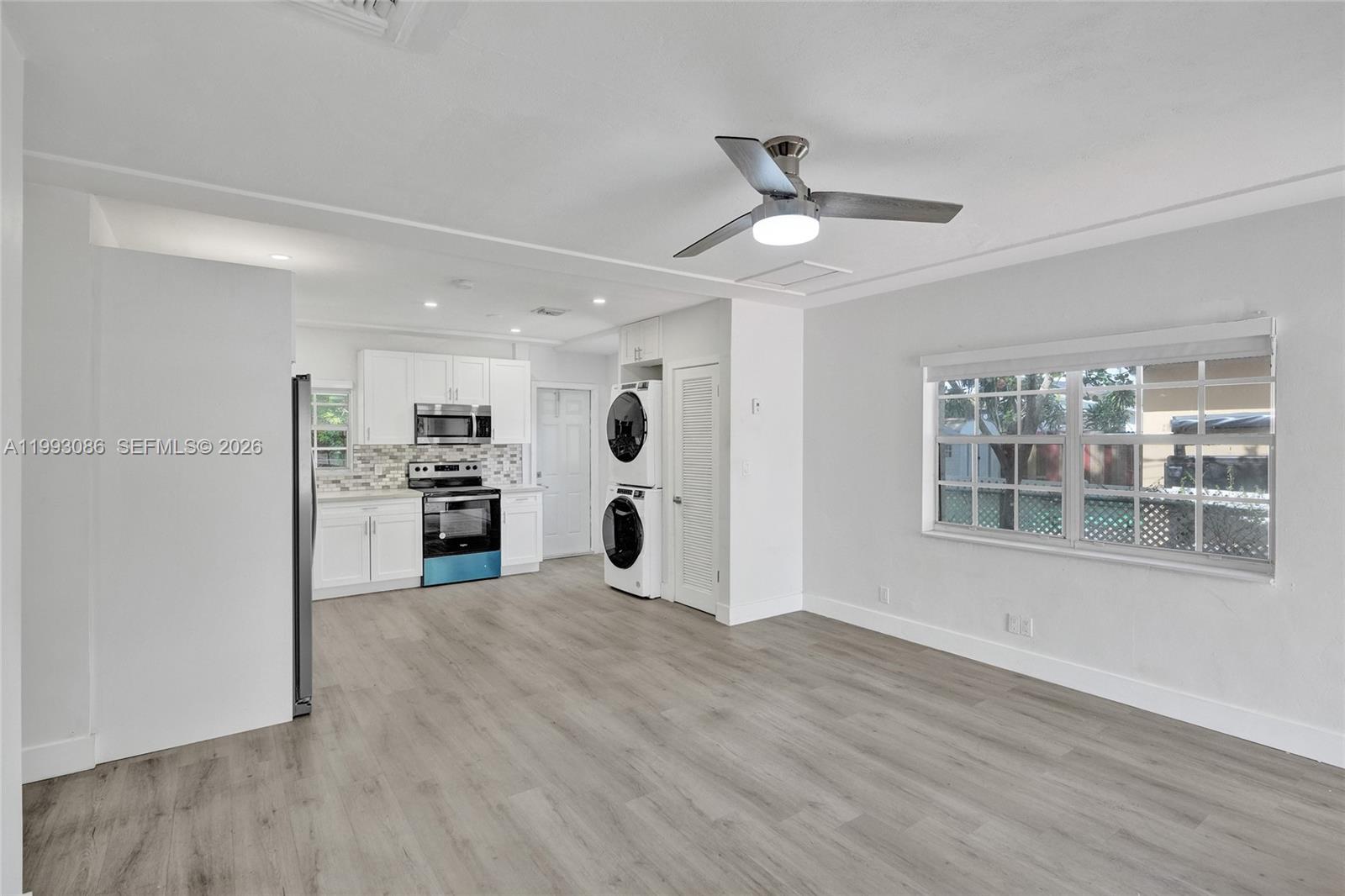 This open-concept kitchen and living area features white cabinetry, stainless appliances, and wood-look flooring — 4326 NW 4th St, Miami FL 33126, MIAMI, FL