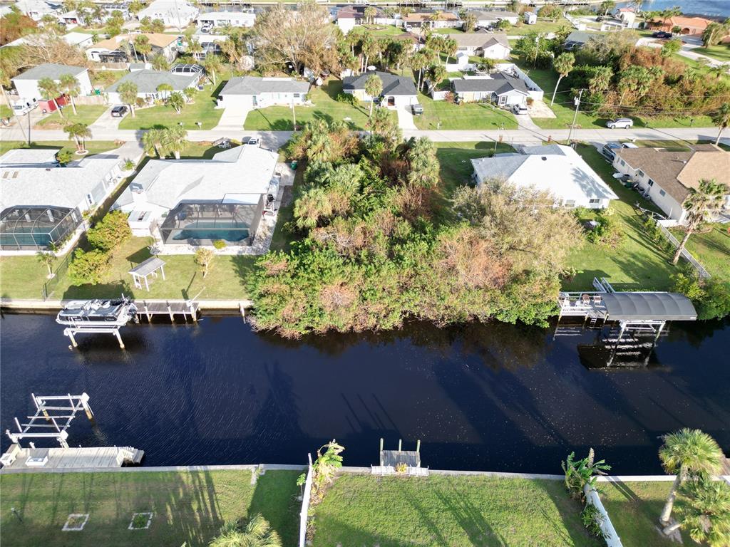 An aerial view shows a canal-front residential lot with a dense cluster of trees — 4194 YUCATAN CIRCLE, PORT CHARLOTTE, FL