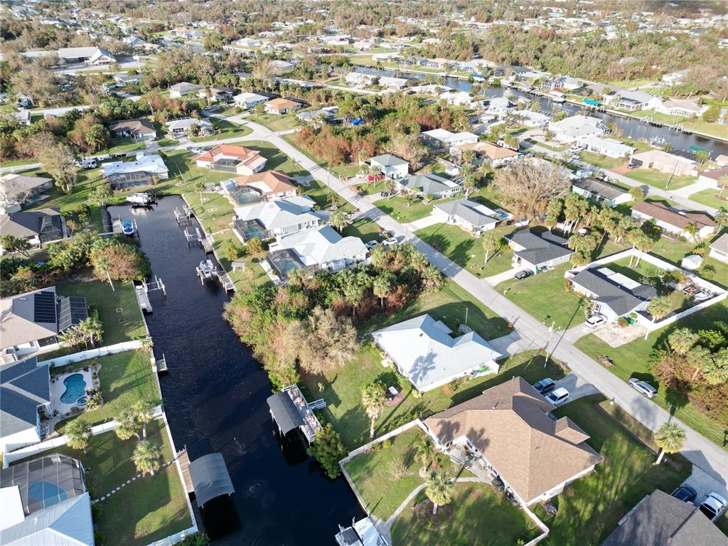 An aerial view shows a residential neighborhood with houses along a canal and streets — 4194 YUCATAN CIRCLE, PORT CHARLOTTE, FL