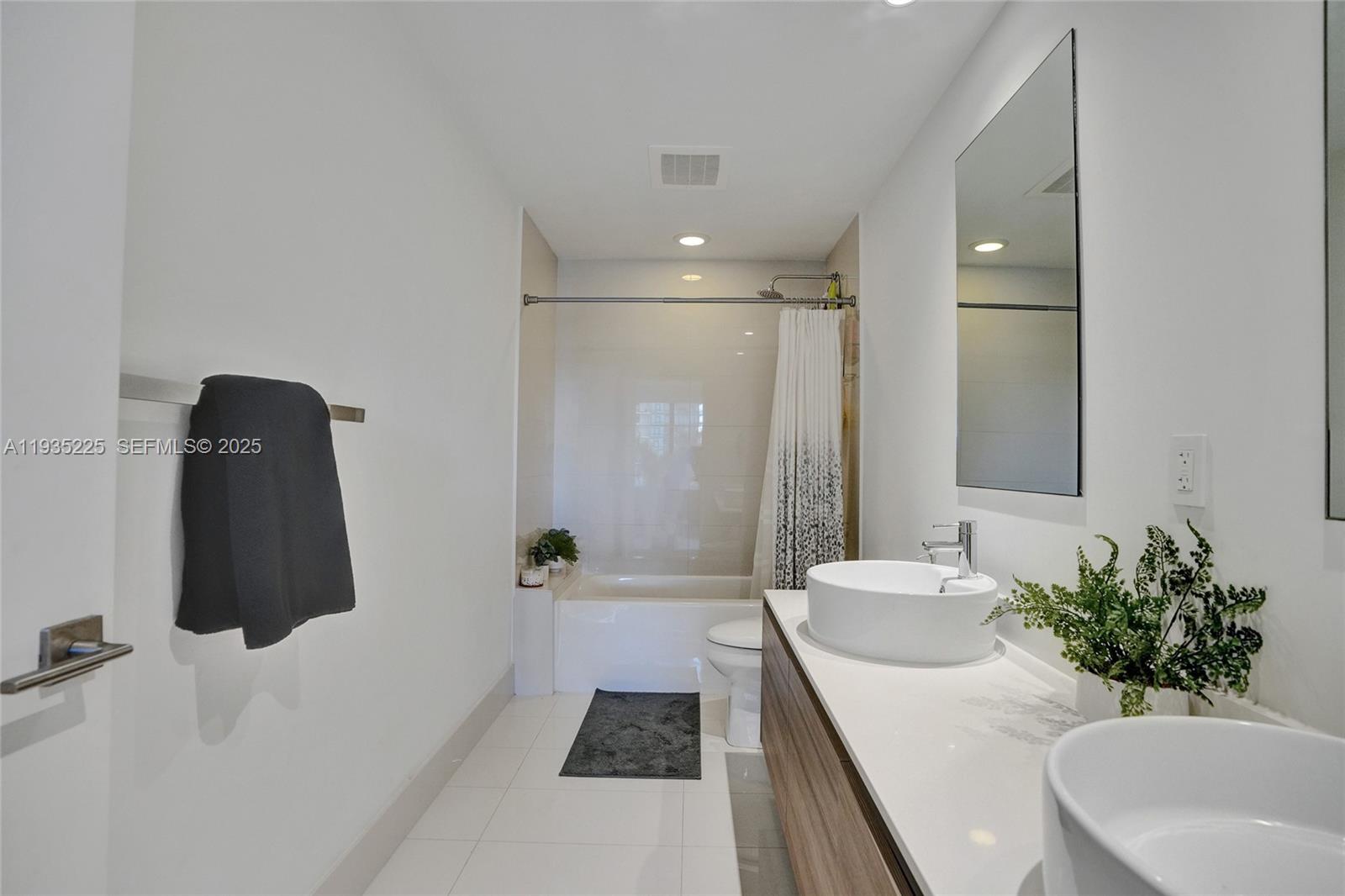 A modern bathroom features a double vanity, a white countertop, and a shower-tub combination — 121 NE 34th St # 902, Miami FL 33137, MIAMI, FL