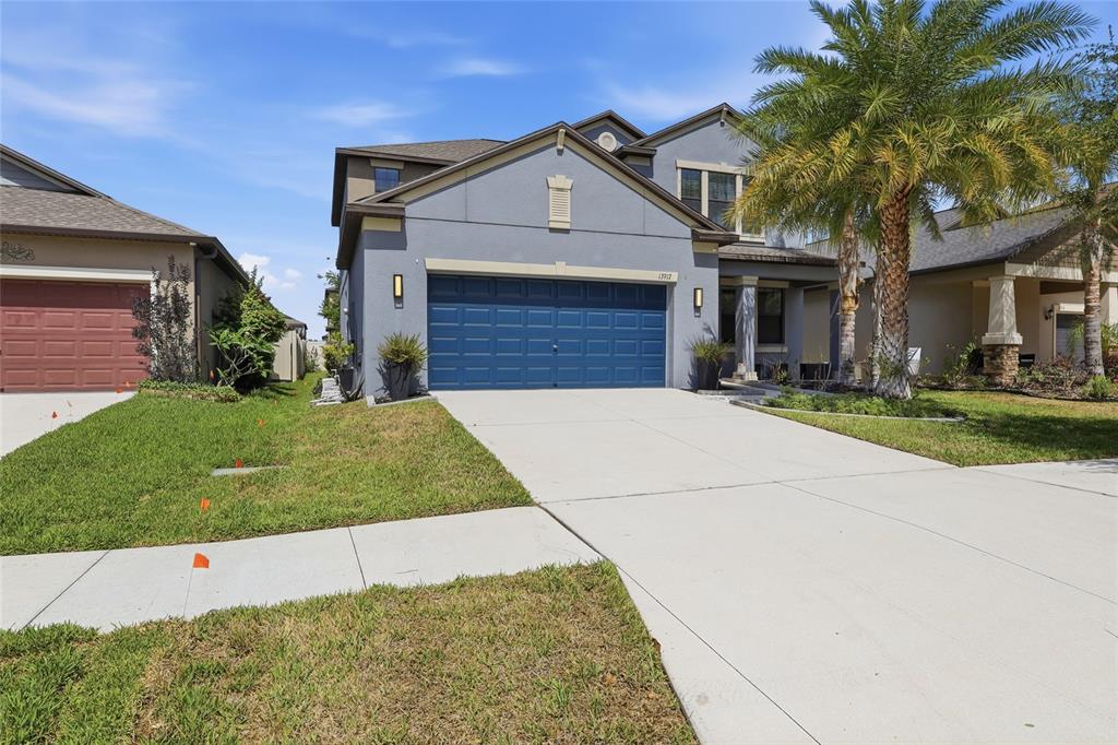 A two-story blue house with a two-car garage and a palm tree in the front — 13917 ROSEATE TERN LANE, RIVERVIEW, FL