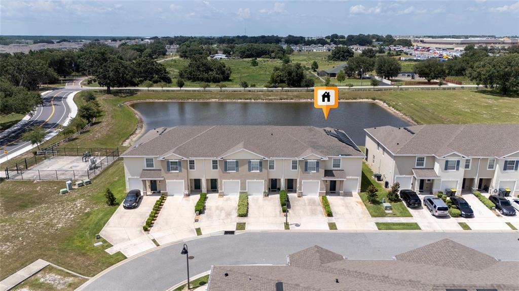 An aerial view shows a row of townhouses with garages facing a pond — 265 FELTRIM RESERVE BOULEVARD, DAVENPORT, FL