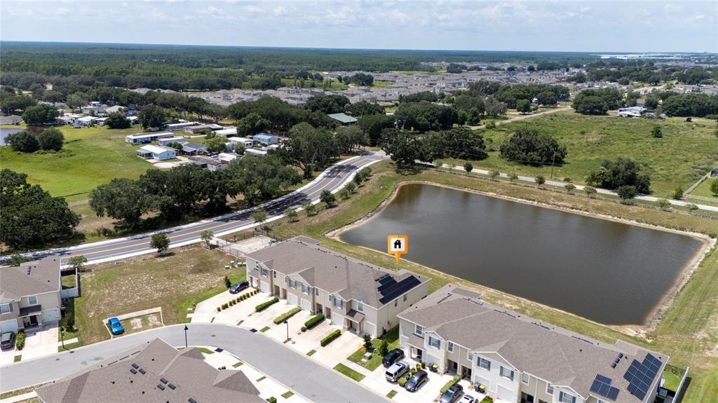 An aerial view shows townhouses with solar panels situated next to a large retention pond — 265 FELTRIM RESERVE BOULEVARD, DAVENPORT, FL