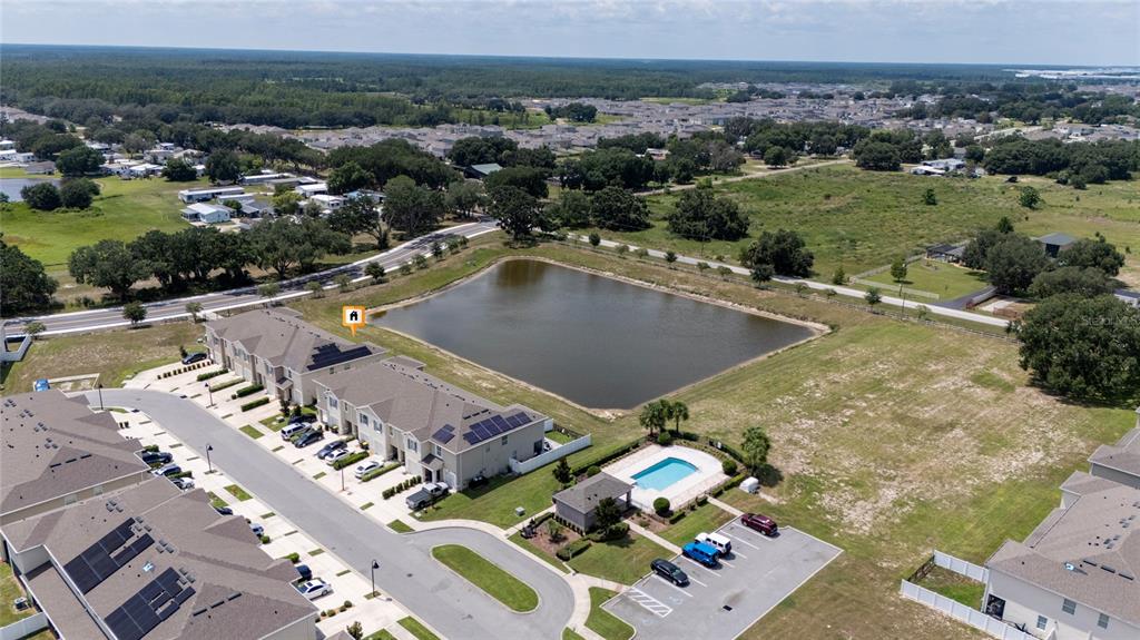 An aerial view shows a townhome complex with a community pool and a retention pond — 265 FELTRIM RESERVE BOULEVARD, DAVENPORT, FL