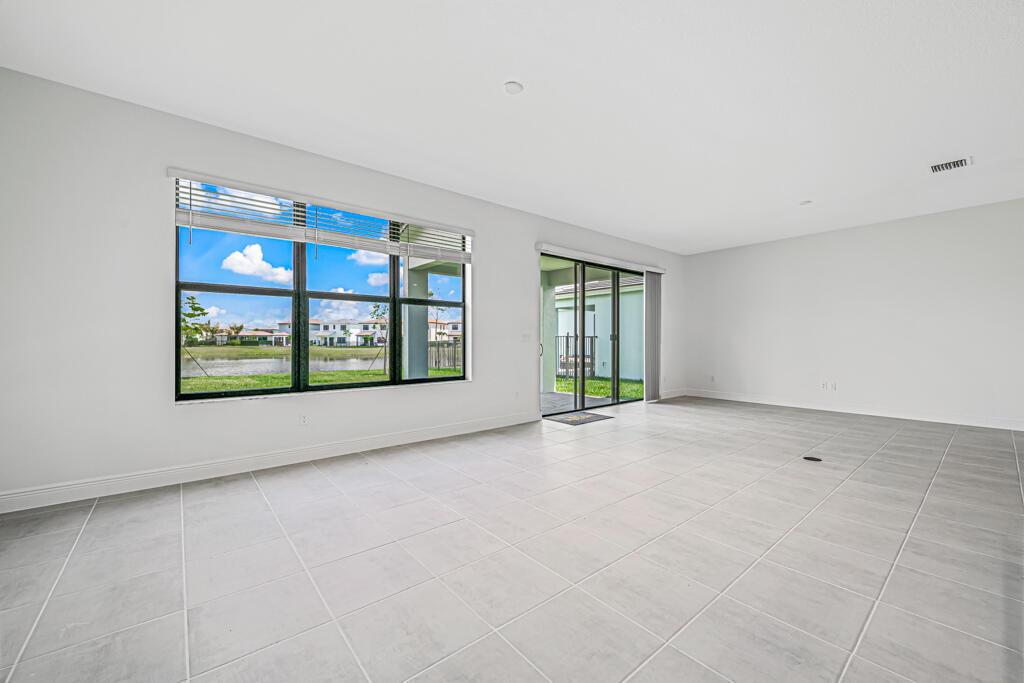 An empty room with light gray tile flooring, large windows, and sliding glass patio doors — 16469 Sea Turtle Place, Westlake FL 33470, WESTLAKE, FL