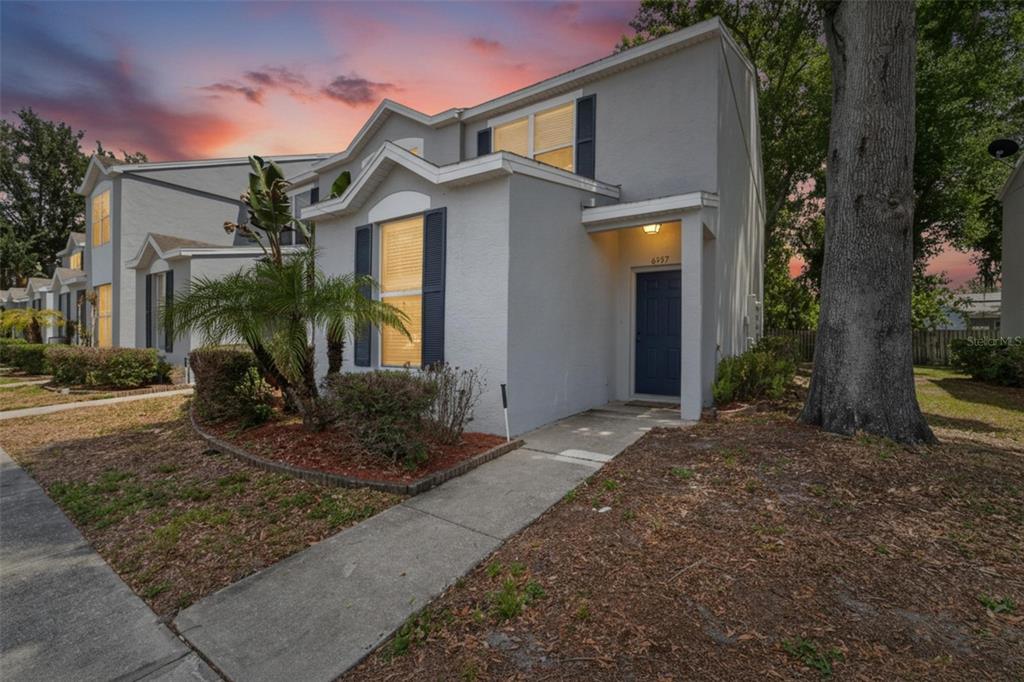 A two-story gray townhouse with a blue front door and a concrete walkway at dusk — 6557 OSPREY LAKE CIRCLE, RIVERVIEW, FL