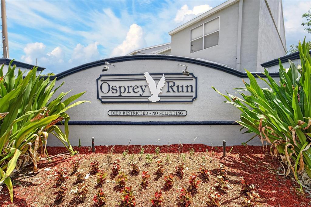 A sign for Osprey Run stands in front of a building with landscaping — 6557 OSPREY LAKE CIRCLE, RIVERVIEW, FL