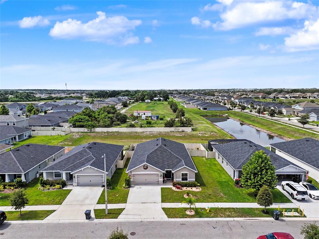 An aerial view shows suburban houses with gray roofs, concrete driveways, and a nearby pond — 11820 STONE PINE STREET, RIVERVIEW, FL