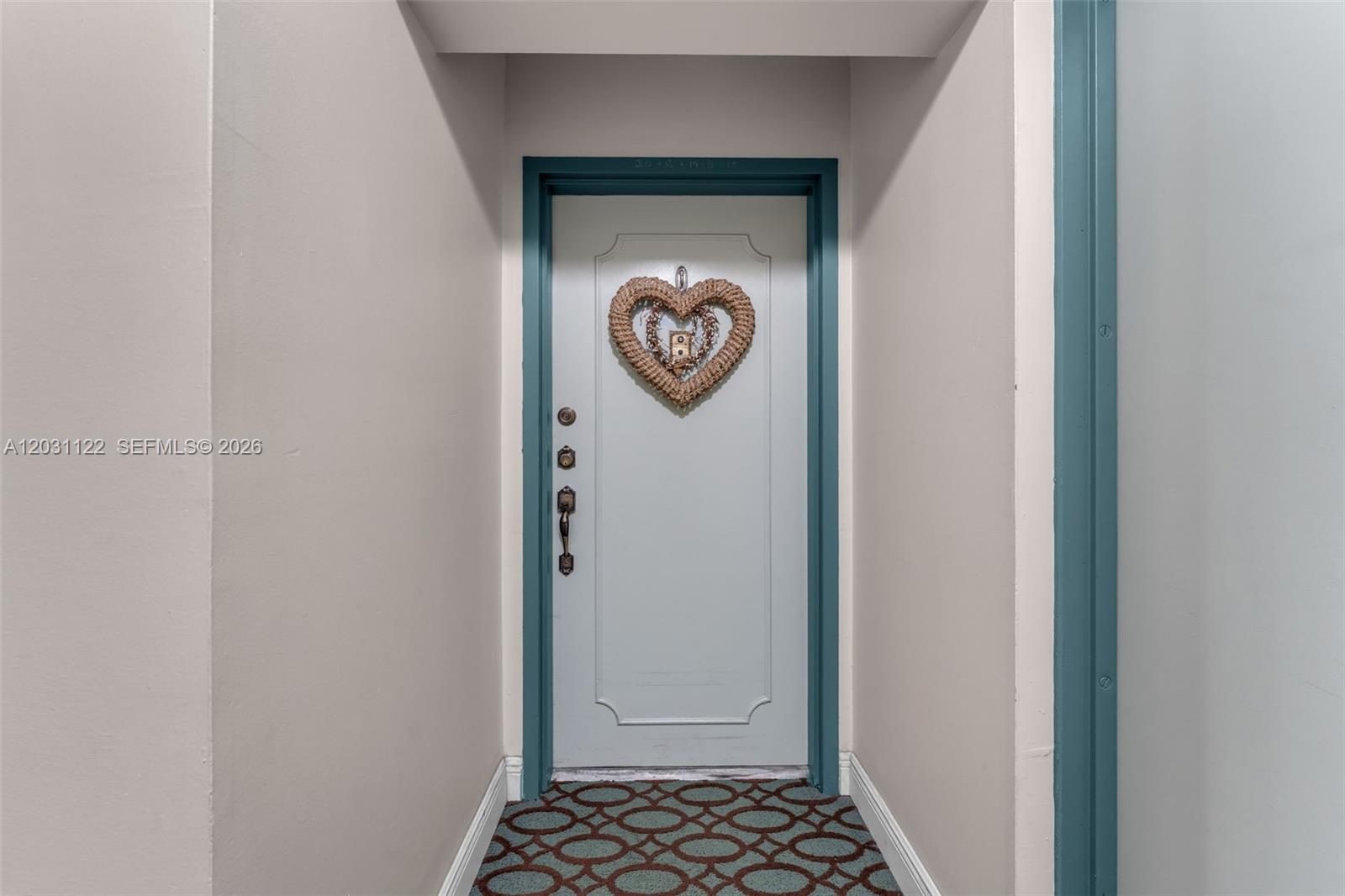 A light-colored door with a heart-shaped wreath sits at the end of a narrow hallway — 6911 SW 147th Ave # 2H, Miami FL 33193, MIAMI, FL