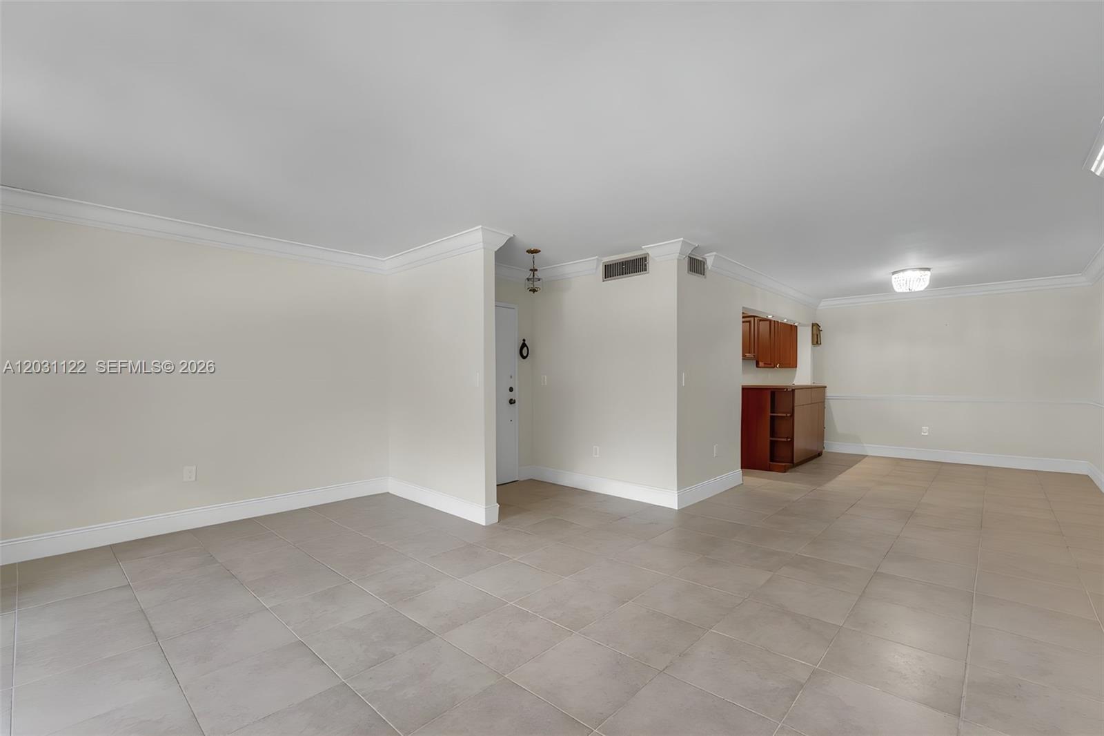 An open-concept living area features light-colored tile flooring, crown molding, and a small wet bar — 6911 SW 147th Ave # 2H, Miami FL 33193, MIAMI, FL