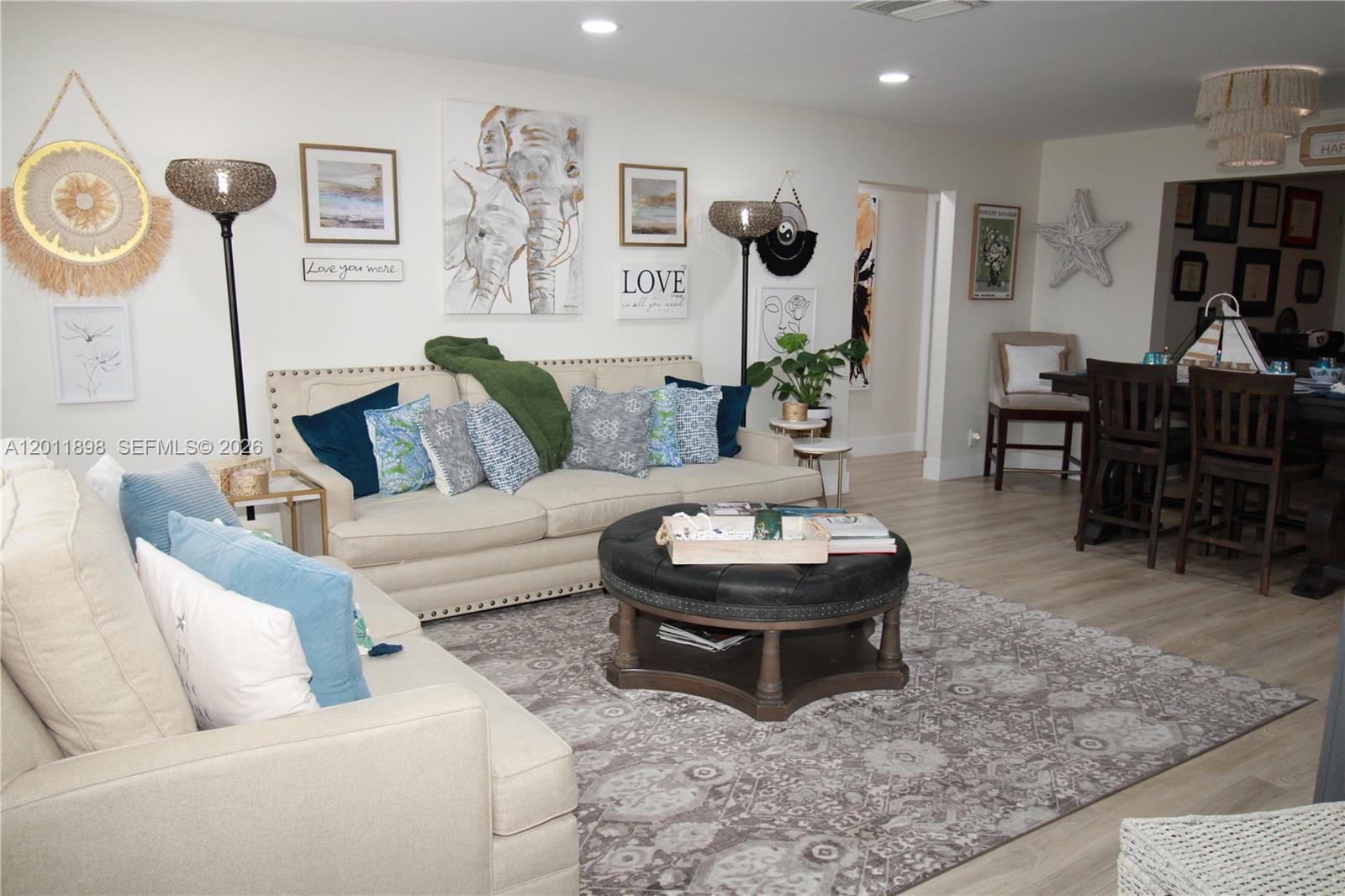 A living room features a beige sofa, a round leather ottoman, and wall art — 1511 Alfred Dr, Boynton Beach FL 33426, BOYNTON BEACH, FL
